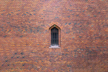 The Window Of The Old Castle Is Closed By A Metal Lattice In A Brick Wall.