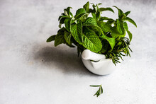 Fresh Rosemary And Mint Herbs In A Mortar And Pestle On A Table