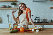 © gstockstudio - Playful young woman using whisk like microphone while cooking at the domestic kitchen