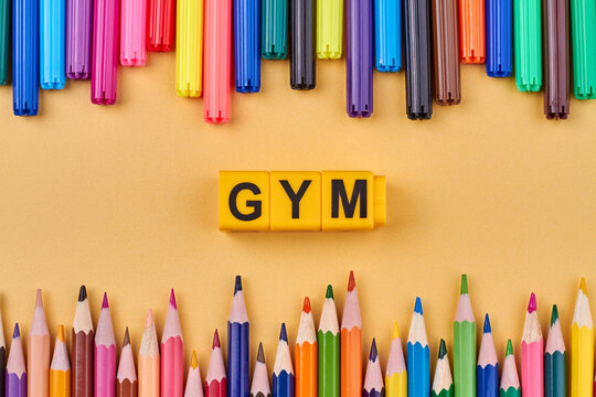Gym word written on color cubes in frame from colorful pencils. Flat lay composition.