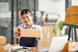 © David - Young Asian entrepreneur SME woman checking product on stock take note with a laptop. Small business owner working at home. Check address on the parcel SME online start up freelance concept.