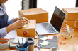 © David - Young Asian entrepreneur SME woman checking product on stock take note with a laptop. Small business owner working at home. Check address on the parcel SME online start up freelance concept.