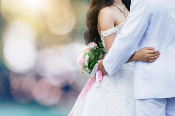 the bride and groom  take pre-wedding photography bokeh background in the groom's hand is hold a wedding bouquet and the wedding dress is specially made, this is their first wedding.