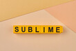 Word sublime written on yellow blocks against color background. Persons attitude or behaviour concept.