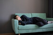 © Mihail - young guy lying and sleeping on the sofa at home in the afternoon
