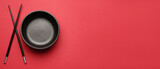 Fototapeta Kawa jest smaczna - Chinese bowl with chopsticks on red background with space for text