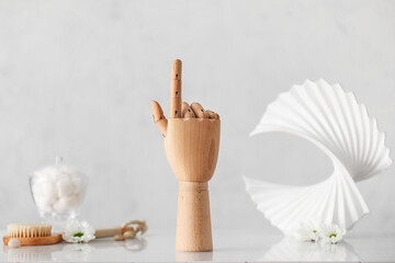 Wooden hand with massage brush and decor on light background