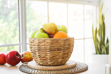 Wicker basket with fresh fruits on dining table, closeup