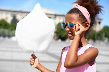 Little African-American girl with cotton candy outdoors