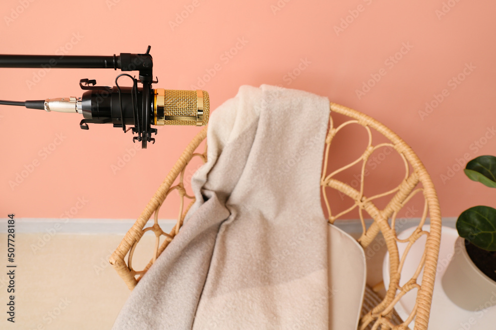 Stand with professional microphone and chair near color wall