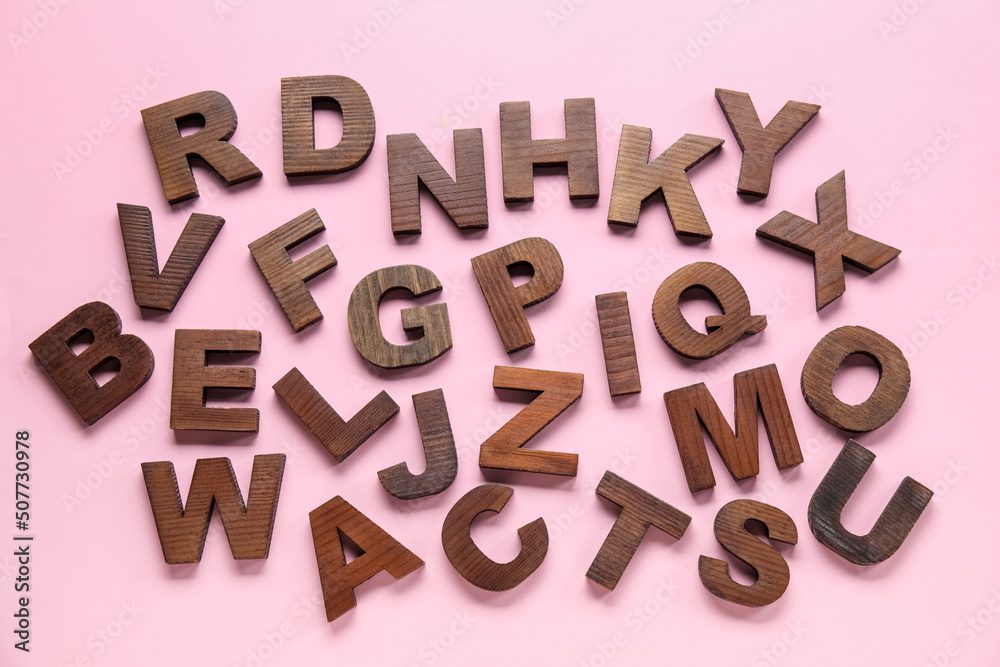 Wooden letters on pink background. Alphabet concept