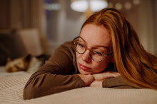 Sad Redhead Woman Lying On Bed At Home