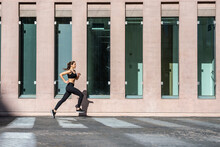 Young Woman Jogging On Footpath By Building