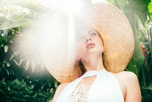 Portrait Of Young Woman Wearing Straw Hat Illuminated By Sunlight