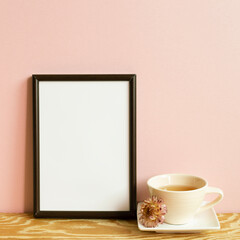 Wall Mural - Picture frame and cup of tea on wooden table. pink wall background. copy space