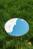 Fototapeta Desenie - nature concept - blue sky and cloud reflection in round mirror on grass