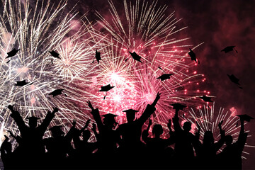 Wall Mural - Graduation ceremony, fireworks in night sky. Silhouette of happy graduate students throwing academic square caps.