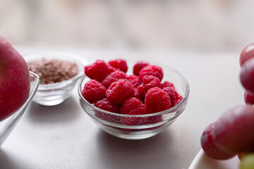 Fresh raspberries in glass bowl on kitchen counter, healthy food for diet.