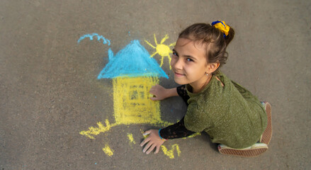 Wall Mural - Children draw the Ukrainian flag house on the pavement. Selective focus.