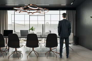Aufkleber - Attractive thoughtful young european businessman standing in modern meeting room interior with window and city view, furniture. CEO and worker concept.