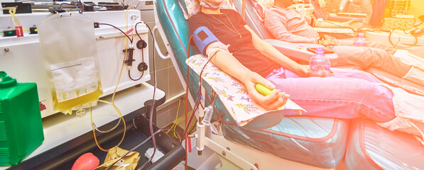 A young man as a blood donor in a donation with an inflatable ball holding in his hand.