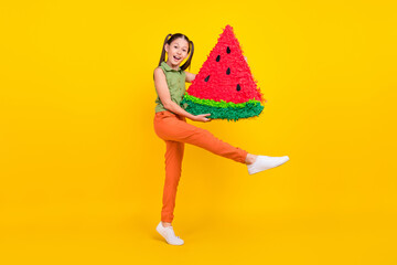 Poster - Photo of hungry excited student girl wear green shirt smiling walking carrying huge watermelon slice isolated yellow color background