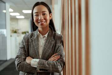 Portrait of attractive asian business woman standing in modern office and looking camera