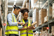 © supAVADEE BUTRADEE - male worker and an African American female worker wearing uniforms pick up a  box to count the number of inventory and pick up  customer's order online to deliver it to a customer in  werehouse.