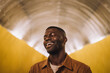 © Maskot - Young man laughing with eyes closed in illuminated tunnel