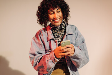 Wall Mural - Cheerful young woman sending a text message on a smartphone