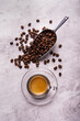 on the textured background, roasted coffee beans and a glass cup with Italian espresso. Copy space.