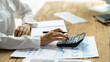 © amnaj - Close-up of businesswoman hands using a calculator to check company finances and earnings and budget. Business woman calculating monthly expenses, managing budget,  papers, loan documents, invoices.
