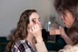 Makeup artist applying eyeshadow to girl's upper eyelid with a brush