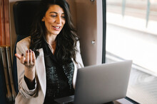 Smiling Businesswoman Doing Video Call On Laptop While Sitting By Window In Train