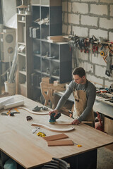 Wall Mural - Mood shot of young carpenter working alone in shop and sanding piece of handcrafted furniture