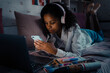 African calm teen girl in headphones scrolling social media