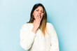 © Asier - Young caucasian woman isolated on blue background yawning showing a tired gesture covering mouth with hand.