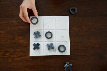 Marble Tic Tac Toe or OX board game. Top view of women hand hold o object playing tic tac toe game. concept of strategy, risk, competition in business.