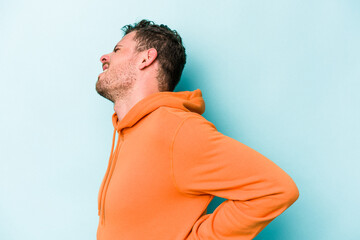 Young caucasian man isolated on blue background suffering a back pain.