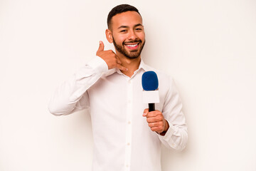 Wall Mural - Young hispanic TV presenter isolated on blue background showing a mobile phone call gesture with fingers.