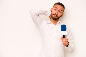 Wall Mural - Young hispanic TV presenter isolated on blue background touching back of head, thinking and making a choice.