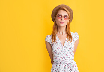 dreamy young woman in straw hat and sunglasses on yellow background