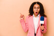 Young African American TV presenter woman isolated on beige background pointing to the side
