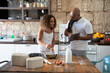 African American man cooking with his daughter while looking at the recipe online on his tablet