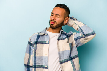 Wall Mural - Young hispanic man isolated on blue background tired and very sleepy keeping hand on head.