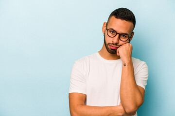 Wall Mural - Young hispanic man isolated on blue background who feels sad and pensive, looking at copy space.