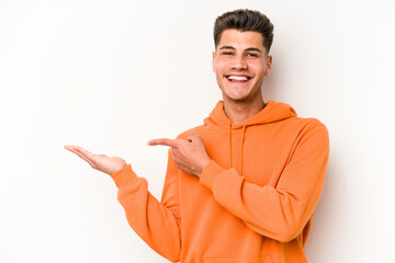 Young caucasian man isolated on white background excited holding a copy space on palm.