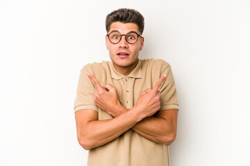 Young caucasian man isolated on white background points sideways, is trying to choose between two options.