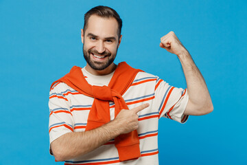 Wall Mural - Young fun strong sporty fitness man in orange striped t-shirt show point index finger on biceps muscles on hand demonstrating strength power isolated on plain blue background People lifestyle concept