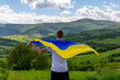 A boy with a flag of Ukraine in the mountains